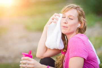  Young Fit Adult Woman Outdoors With Towel and Water Bottle in Workout Clothes Listening To Music with Earphones.