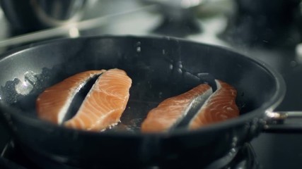 Wall Mural - Close-up of  Pieces of Red Fish Fillet Frying on a Hot Pan. Shot on RED EPIC-W 8K Helium Cinema Camera.