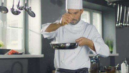 Wall Mural - Professional Chef Squeezes Lemon Juice onto Hot Pan with Red Fish Fillet on it. He Works in a Modern Kitchen. Shot on RED EPIC-W 8K Helium Cinema Camera.