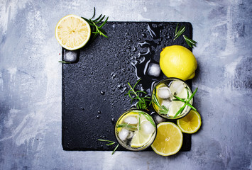 Canvas Print - Summer cocktail with lemon, rosemary and ice, gray background, top view