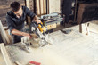 © Виталий Сова - A young male carpenter builder saws a modern circular saw a wooden board in the workshop room