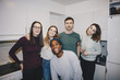 © Maskot - Portrait of happy young friends standing in kitchen at college dorm
