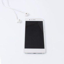 White mobile phone with white headphones on white background