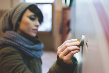 Woman In Knit Hat Inserting Coin Into Railway Ticket Machine