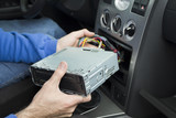 Mechanik wkłada radio samochodowe do kieszeni na radio w samochodzie. Podłączanie radia.