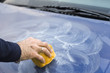 Nakładanie pasty polerskiej na maskę samochodu za pomocą gąbki.