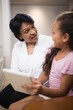 © wavebreak3 - Woman sitting with granddaughter using digital tablet