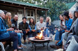 © Trinette Reed/Stocksy - Group of friends and family relaxing around a fire pit at a farm
