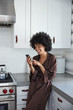 © Trinette Reed/Stocksy - African American woman on her phone in kitchen