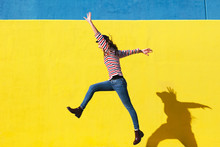 Happy Woman Jumping In Front Of Yellow Background