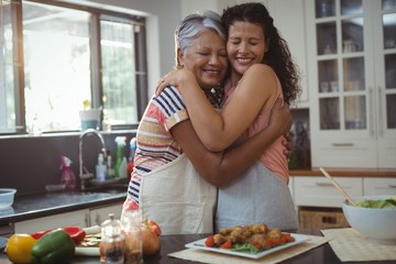 Mother hugging daughter in kitchen