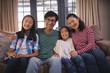 © WavebreakMediaMicro - Smiling family relaxing on sofa in living room