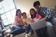 © WavebreakMediaMicro - Family using laptop together in living room