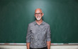 © Rob and Julia Campbell/Stocksy - Happy smiling older gentleman standing near chalkboard