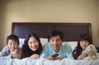 © wavebreak3 - Happy family watching television in the bed room