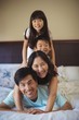 © wavebreak3 - Happy family having fun on bed in the bed room