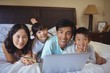 © wavebreak3 - Happy family doing online shopping on laptop in the bed room