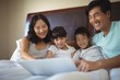 © wavebreak3 - Family using laptop together in bedroom