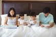© wavebreak3 - Family using electronic devices in bedroom