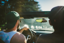 Two Young Men Drive Down A Road In Their Convertible 