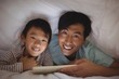 © wavebreak3 - Father and son using digital tablet under blanket in bedroom