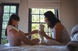 © WavebreakMediaMicro - Daughter and mother playing with teddy bear in bed room