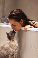 Woman Kissing Her Siamese Cat From The Bathtub