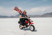 Portrait Of Young Male Wearing American Flag While Riding Motorcycle Through Desert Salt Flat