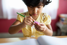 A Little Girl Sharpens A Pencil