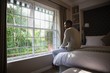 © WavebreakMediaMicro - Man sitting on bed by window in bedroom