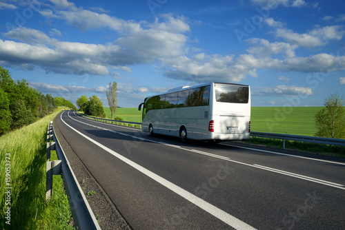 Zdjęcie XXL Autobus poruszający się po asfaltowej drodze wzdłuż zielonych pól i zaułków na wsi
