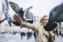 Young Woman Feeding Pigeons In The City