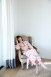 © Trinette Reed/Stocksy - Portrait of woman relaxing on chair in bedroom