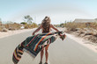 © HOWL/Stocksy - A carefree young woman stands in the middle of a desert road