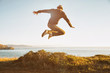 © Trinette Reed/Stocksy - Hipster jumping over bush in nature