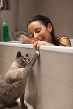 Woman Playing With Her Siamese Cat From The Bathtub