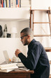 © BONNINSTUDIO/Stocksy - Side view of a latin man working with laptop at home office