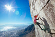 © Micky Wiswedel/Stocksy - Female rock climber climbing a sheer cliff overlooking a city