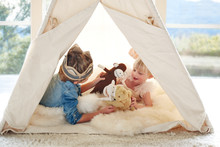 Brother And Sister Playing In Teepee Tent In Living Room