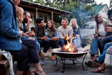 Group Of Friends And Family Relaxing Around A Fire Pit At A Farm