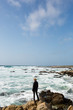© michela ravasio/Stocksy - Woman standing on a rock on the coast of the Pacific Ocean