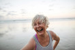 © Rob and Julia Campbell/Stocksy - Vibrant mature woman enjoying herself on the beach at sunset
