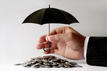 Businessman Protecting Coins With Umbrella. Financial Safety Concept.
