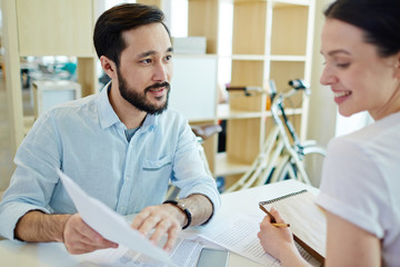 Canvas Print - Two young co-workers discussing business papers at meeting