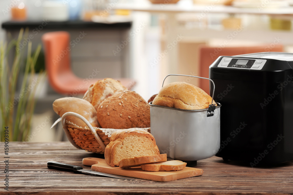 Tasty sliced loaf and bread machine on table