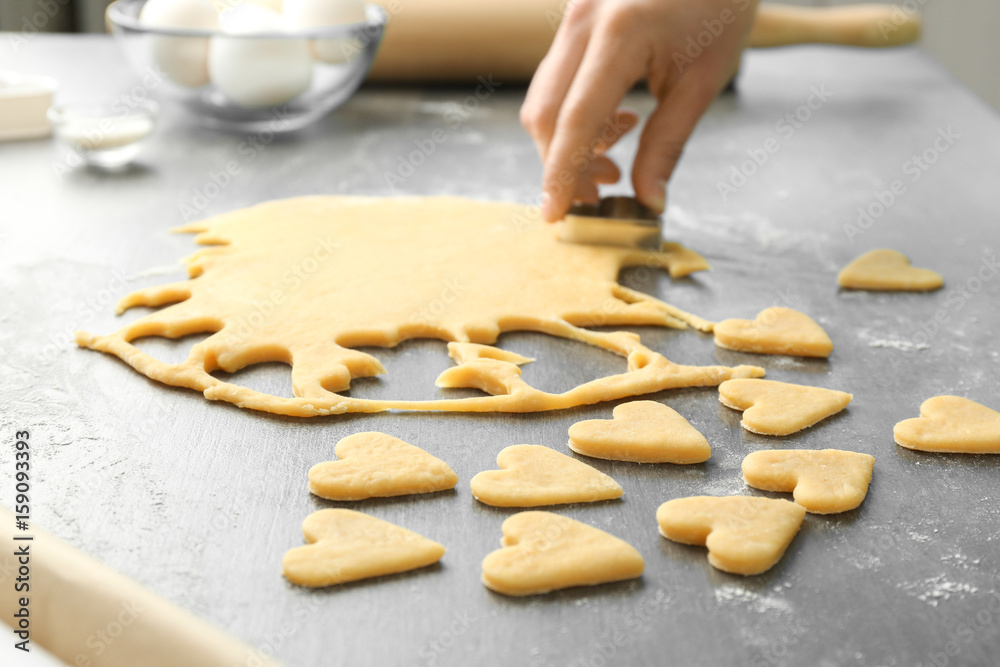 Woman preparing butter cookies on table