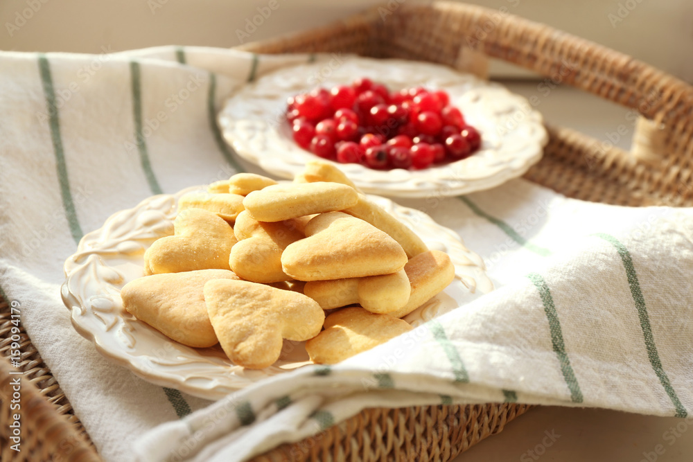 Wicker tray with heart shaped butter cookies on table