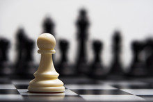 White Pawn Against The Background Of Dark Chess Pieces