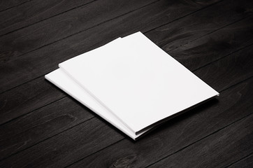 Two blank corporate identity broshure on black stylish wood background, mock up.