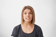 © WHstudio Leushin N - Puzzled beautiful woman with dark eyes and straight dyed hair biting her lower lip looking with surprise into camera. Human face expressions and emotions. European woman posing in white studio